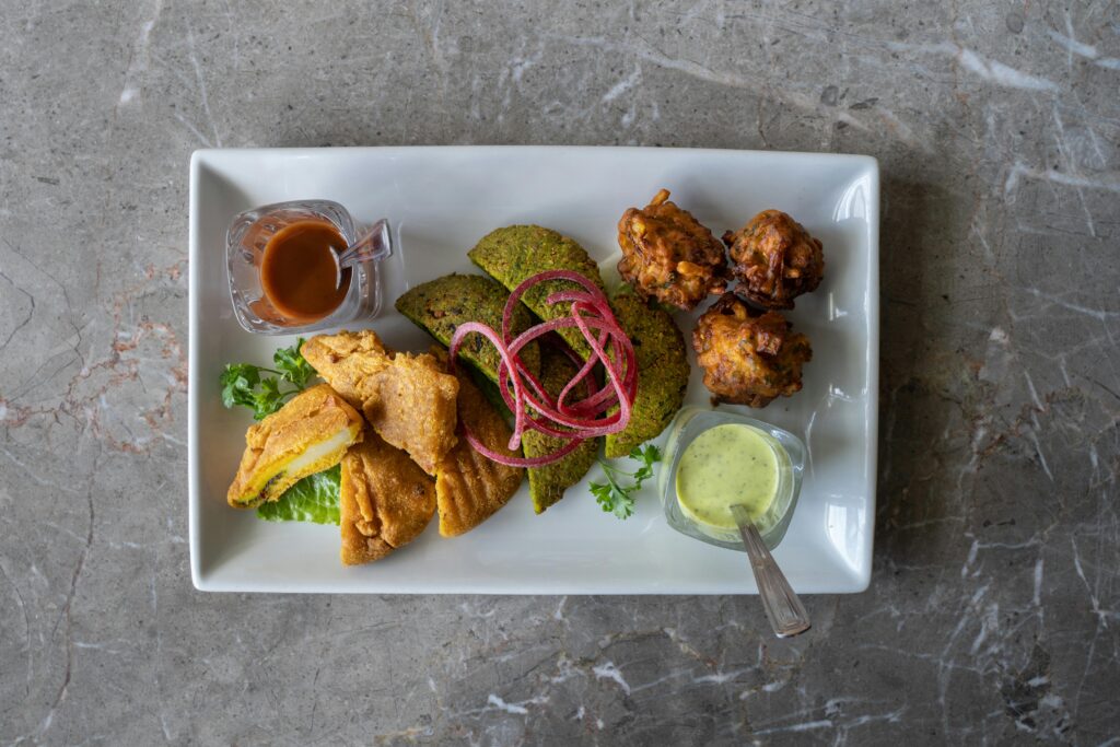 An appetizing Indian food platter with samosas, fritters, chutneys, and salads for a tasty experience.